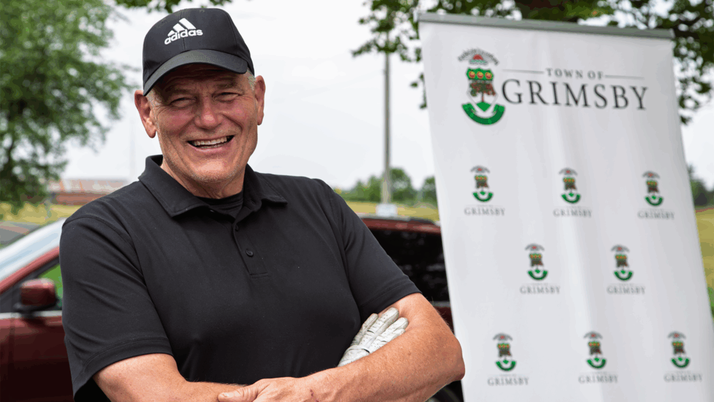 Mayor Jeff Jordan at the Town of Grimsby Golf Tournament outside in front of promotional banner