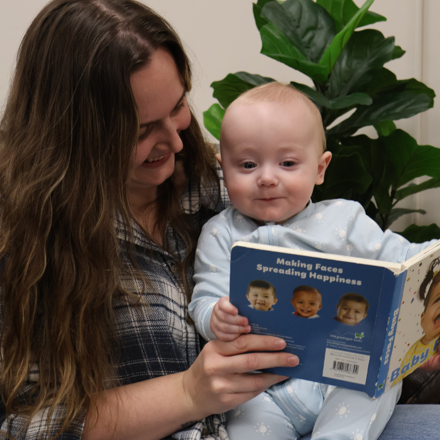Mother or caregiver with baby reading book together